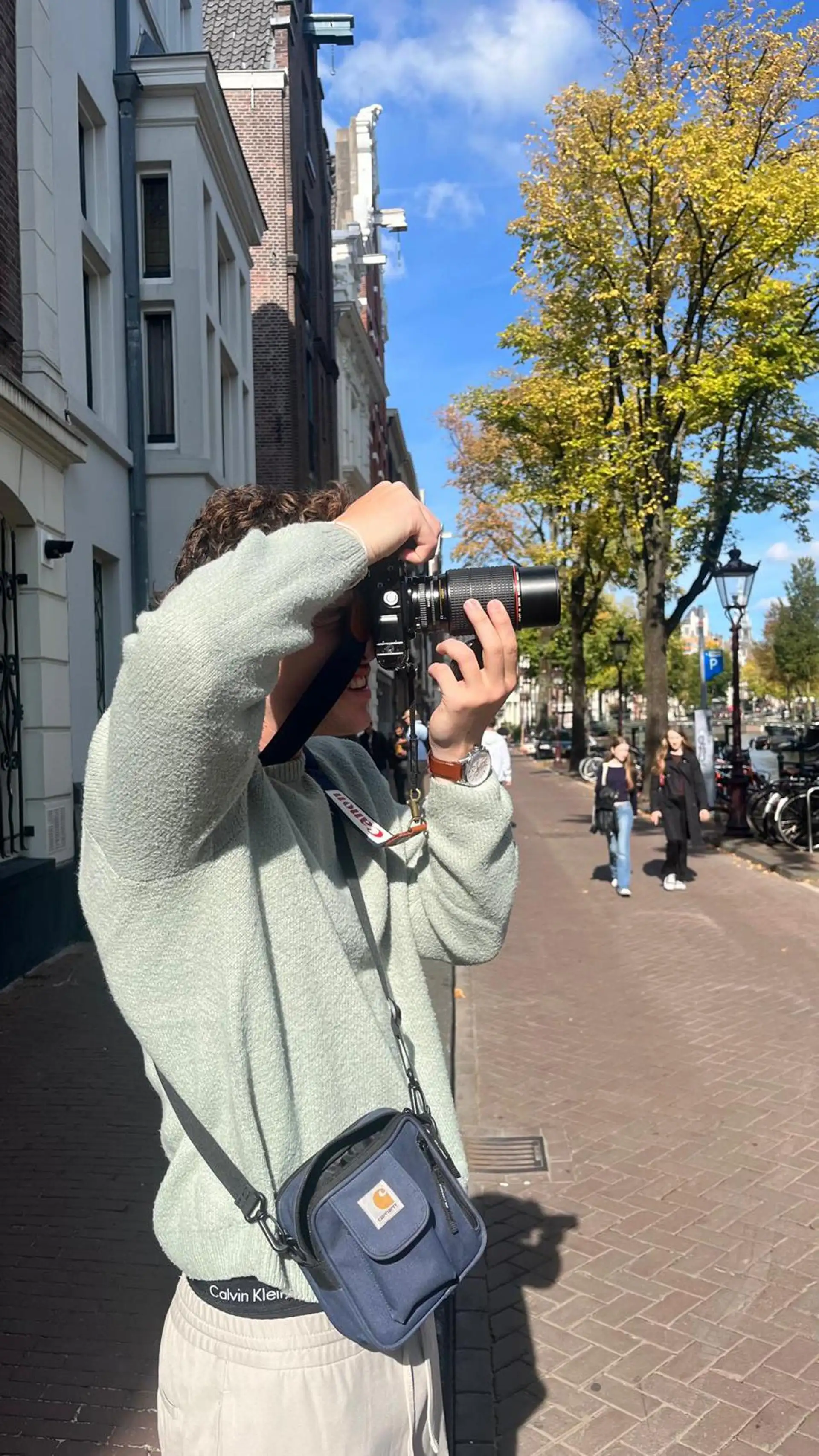Toerist fotografeert een gracht in Amsterdam tijdens de fotowandeling